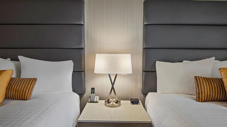 A lamp between two beds in the Select Room at Best Western Premier Calgary Plaza Hotel